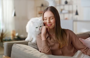 Leverancier-Purina-Gourmet-Revelations-kat-vrouw-in-zetel-met-witte-kat